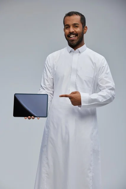 Saudi Man in White Thobe Pointing at Digital Tablet