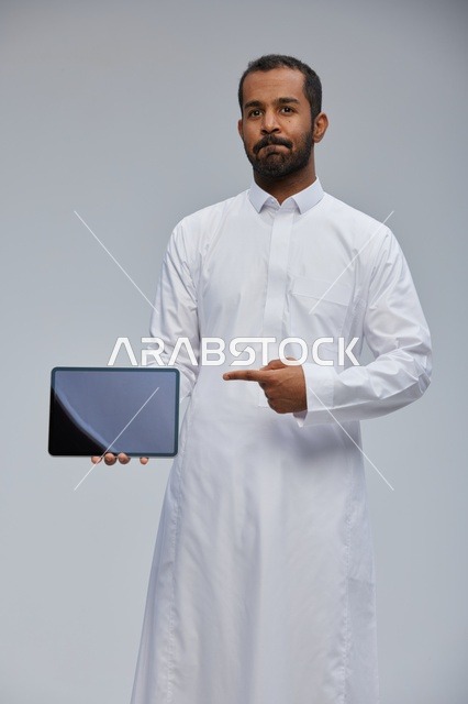 رجل سعودي بالثوب يشير إلى جهاز لوحي