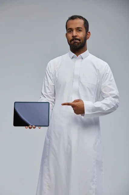 رجل سعودي بالثوب يشير إلى جهاز لوحي