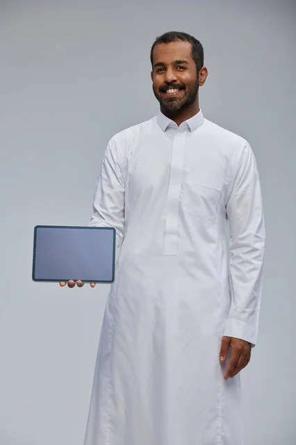 Saudi Man in White Thobe Holding Tablet Device