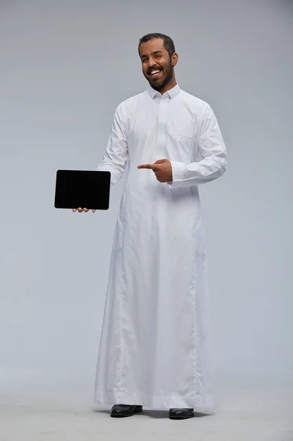رجل سعودي بالثوب الأبيض يعرض جهاز لوحي في الاستوديو