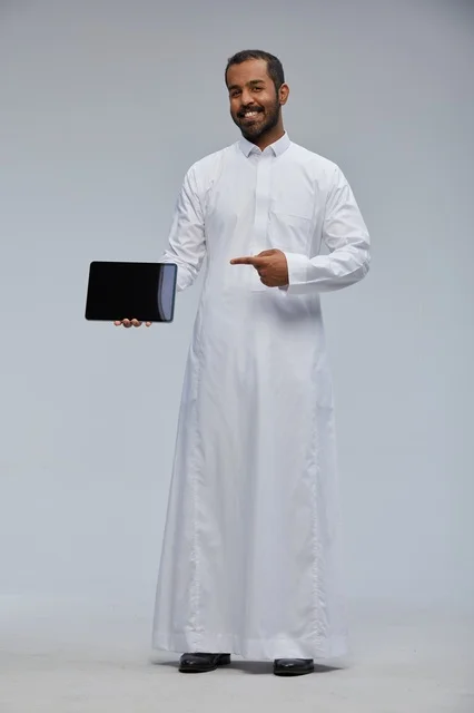 Saudi Man in White Thobe Pointing at Digital Tablet