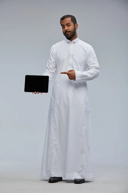 Saudi Man in White Thobe Holding Digital Tablet Device
