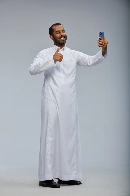 رجل سعودي بالثوب الأبيض يلتقط سيلفي بالهاتف الذكي