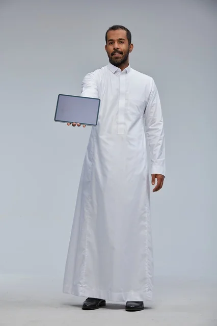 رجل سعودي بالثوب التقليدي يعرض جهازاً لوحياً رقمياً