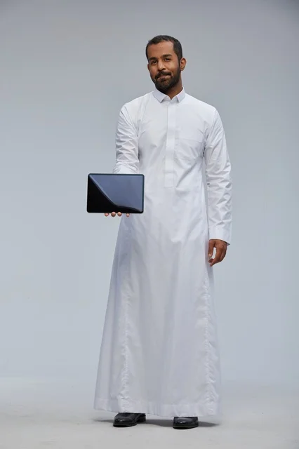 Saudi Man in White Thobe Holding Digital Tablet