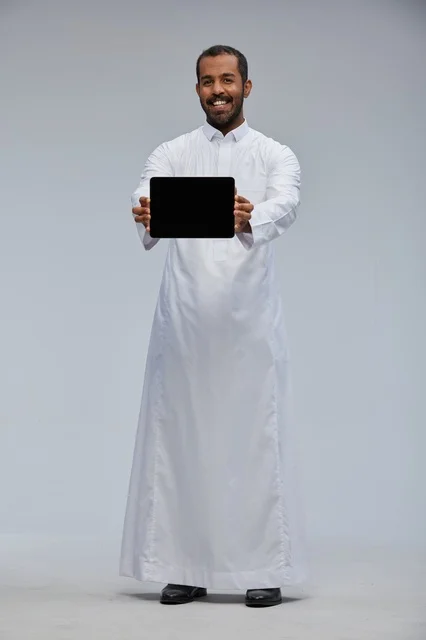 رجل سعودي بالثوب التقليدي يمسك جهاز لوحي شاشة سوداء