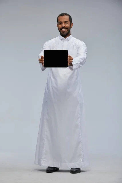 رجل سعودي بالثوب الأبيض يعرض جهازاً لوحياً