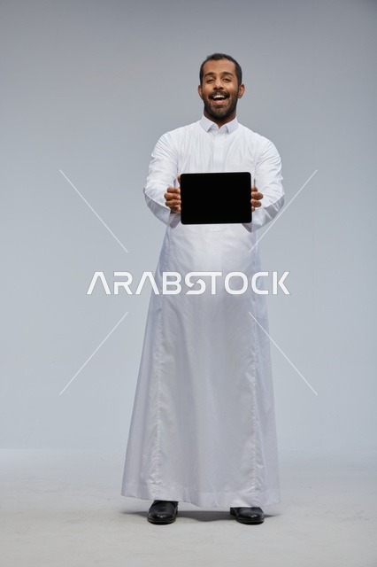 رجل سعودي بالثوب الأبيض يعرض جهاز لوحي