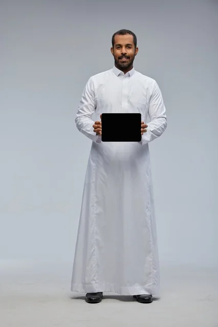 Saudi Man in White Thobe Holding Digital Tablet