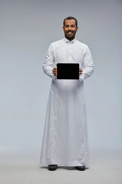 Saudi Man in White Thobe Holding Digital Tablet