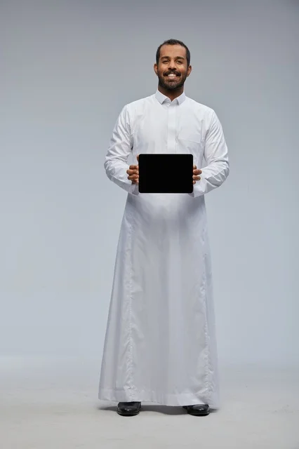 رجل سعودي بالثوب الأبيض يحمل جهاز لوحي في الاستوديو