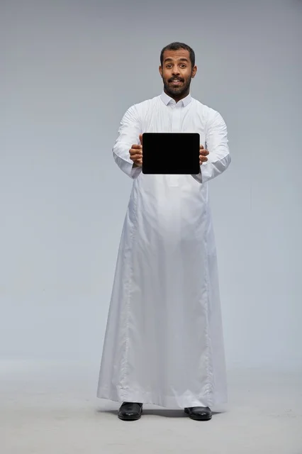 Saudi Man in White Thobe Holding Tablet in Studio