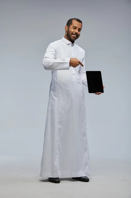 رجل سعودي بالثوب الأبيض يحمل جهازاً لوحياً