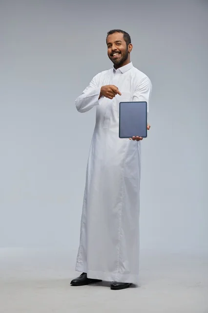 Saudi Man in White Thobe Holding Digital Tablet