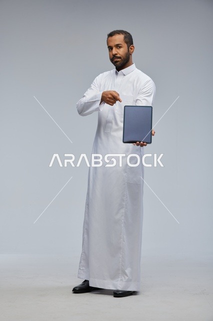 رجل سعودي بالثوب الأبيض يعرض جهاز لوحي