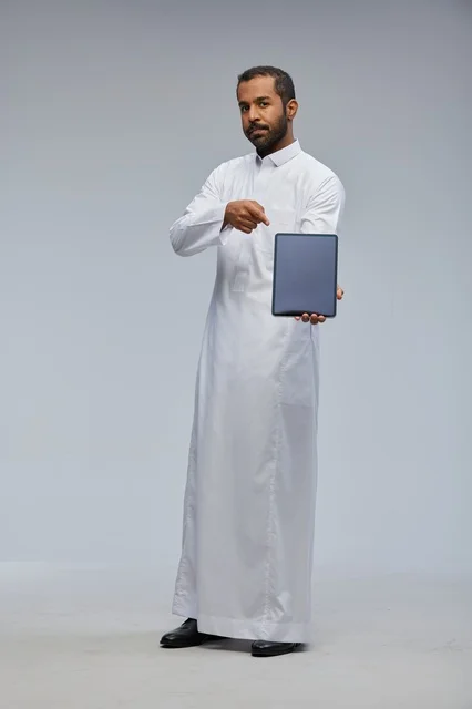 رجل سعودي بالثوب الأبيض يعرض جهاز لوحي
