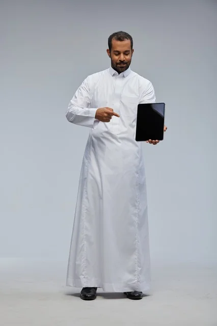 Saudi Man in White Thobe Holding Tablet Studio Shot