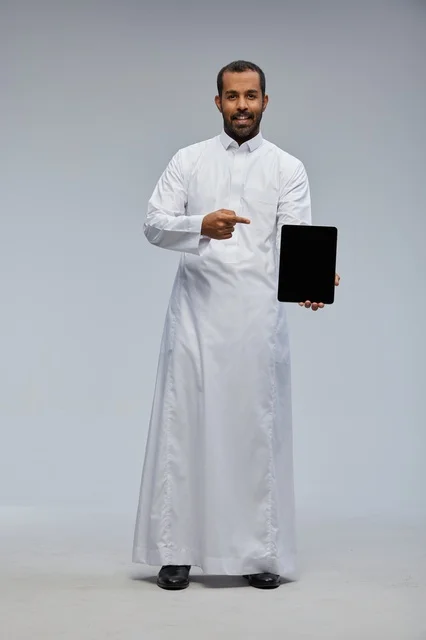 Saudi Man in Traditional Thobe Pointing at Tablet Screen