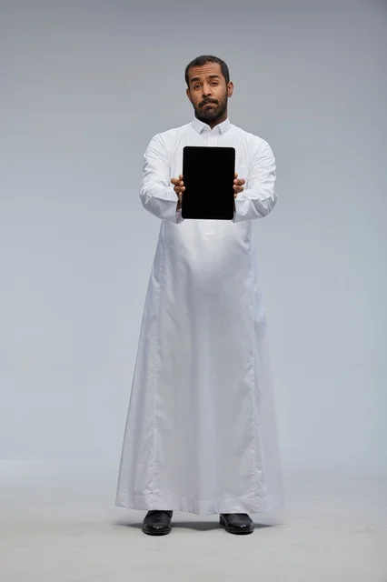 Saudi Man in White Thobe Holding Digital Tablet Device