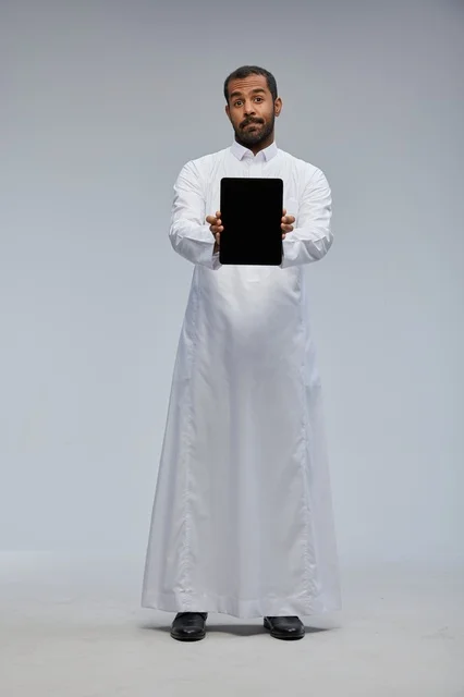 Saudi Man in White Thobe Holding Digital Tablet