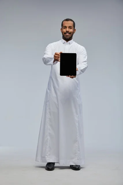 Saudi Man in Thobe Holding Tablet on Grey Background