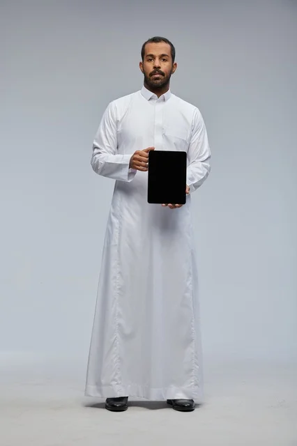 رجل سعودي يرتدي الثوب الأبيض ويمسك جهاز لوحي رقمي