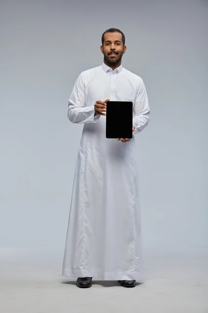 رجل سعودي بالثوب الأبيض يمسك جهاز لوحي رقمي