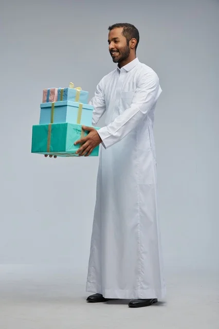 Saudi Man in White Thobe Holding Wrapped Gift Boxes