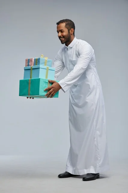 رجل سعودي بالزي التقليدي يحمل صناديق هدايا