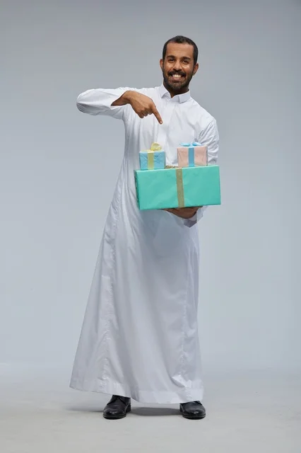 رجل سعودي بالزي التقليدي يحمل صناديق هدايا ملونة