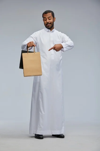 رجل سعودي بالثوب يحمل أكياس تسوق في الاستوديو