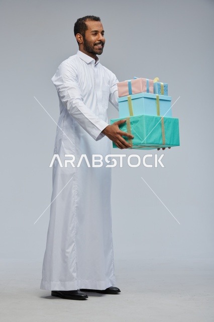 رجل سعودي بالثوب التقليدي يحمل صناديق هدايا