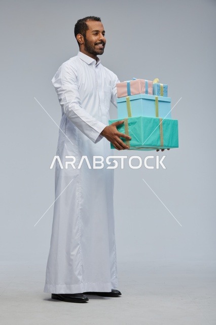 رجل سعودي بالزي التقليدي يحمل مجموعة صناديق هدايا