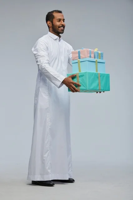 رجل سعودي بالزي التقليدي يحمل مجموعة صناديق هدايا