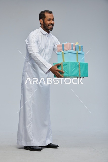 رجل سعودي بالثوب التقليدي يحمل صناديق هدايا مغلفة