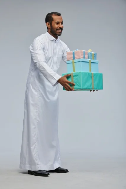 رجل سعودي بالثوب التقليدي يحمل صناديق هدايا مغلفة