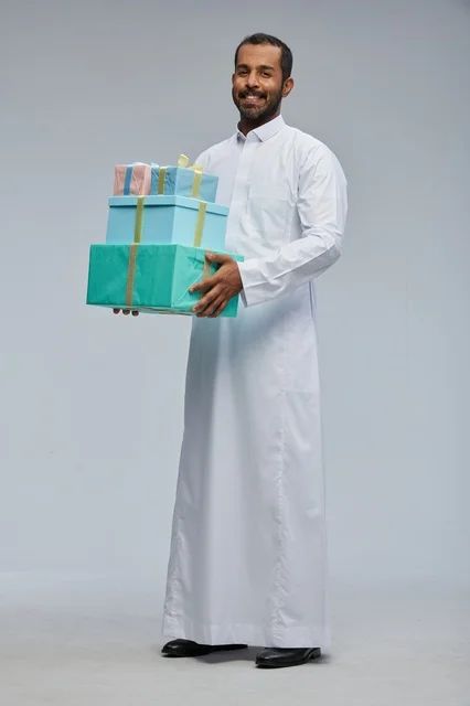 رجل سعودي بالثوب التقليدي يحمل صناديق هدايا