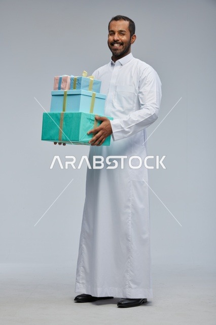 رجل سعودي بالزي التقليدي يحمل صناديق هدايا ملونة