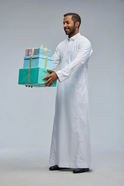رجل سعودي بالثوب التقليدي يحمل صناديق هدايا ملونة