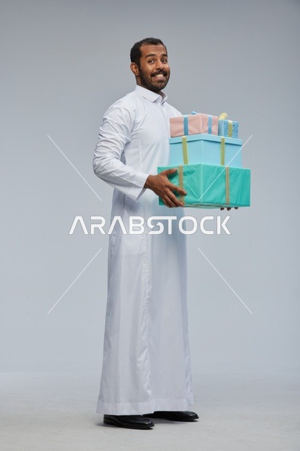 رجل سعودي بالثوب التقليدي يحمل صناديق هدايا ملونة