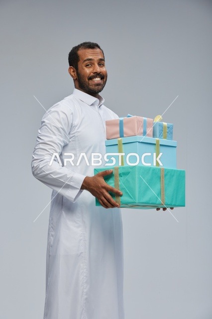 رجل سعودي بالثوب يحمل صناديق هدايا مغلفة