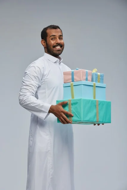 رجل سعودي بالثوب يحمل صناديق هدايا مغلفة