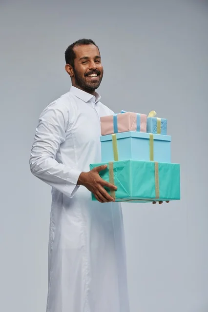 رجل سعودي بالزي التقليدي يحمل صناديق هدايا