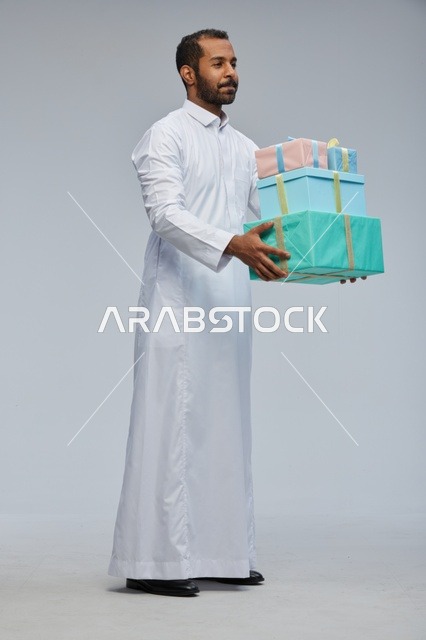 رجل سعودي بالثوب التقليدي يحمل صناديق هدايا