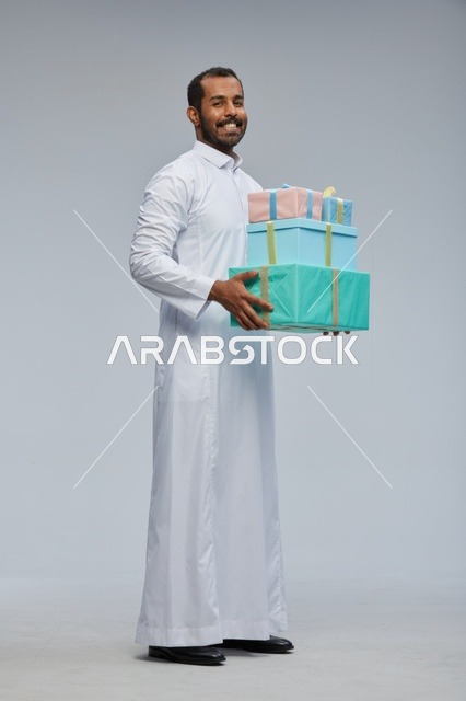 رجل سعودي بالزي التقليدي يحمل صناديق هدايا ملونة