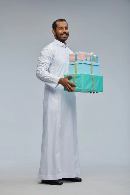 رجل سعودي بالزي التقليدي يحمل صناديق هدايا ملونة
