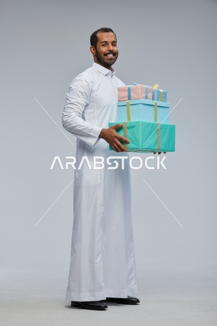 رجل سعودي بالثوب التقليدي يحمل صناديق هدايا ملونة