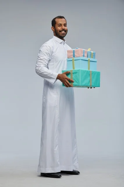 رجل سعودي بالثوب التقليدي يحمل صناديق هدايا ملونة