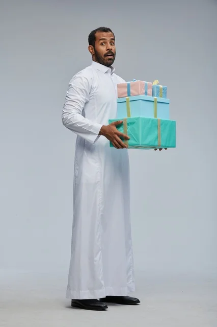 رجل سعودي بالزي التقليدي يحمل صناديق هدايا ملونة